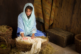 Teenager girl playing the role of the Virgin Mary with a doll in a live Christmas nativity scene